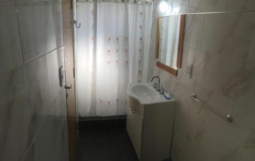 y baño blanco con lavabo y ducha. en Alquileres Bosero en Las Toninas