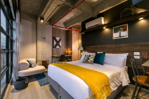 a bedroom with a large bed and a chair at Factory Lofts Hotel in Medellín
