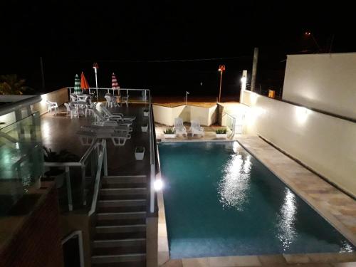 a swimming pool at night with a table and chairs at Pousada Elegance Beira Mar in Itanhaém