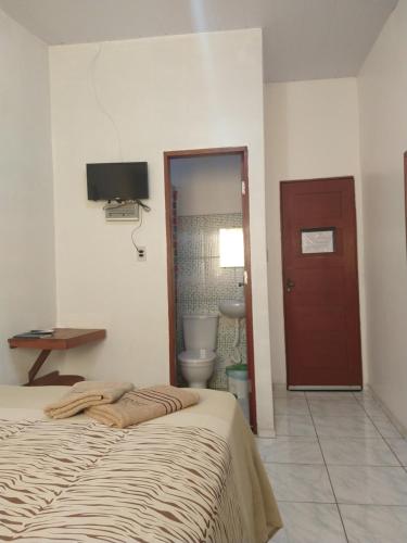 a bedroom with a bed and a toilet and a television at Pousada Jatobá in Barreirinhas