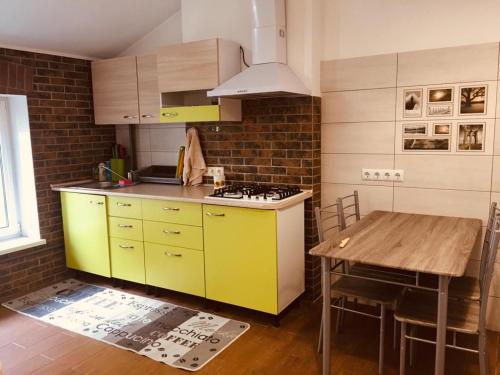 a kitchen with yellow cabinets and a wooden table at Comfort place in the city centre in Ivano-Frankivsʼk