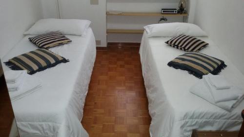 Cette chambre comprend 2 lits avec des draps et des oreillers blancs. dans l'établissement STANZA Juventus, con servizio navetta a richiesta, à Turin