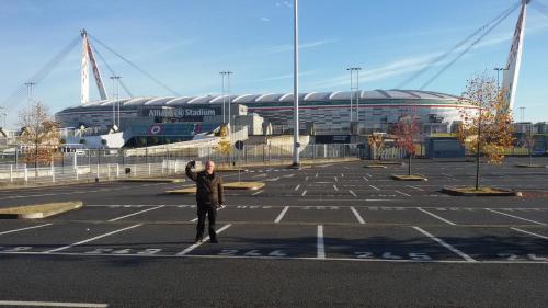 Un homme debout dans un parking en face d'un stade dans l'établissement STANZA Juventus, con servizio navetta a richiesta, à Turin