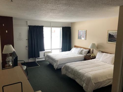 um quarto de hotel com duas camas e uma janela em Jockey Motel em Edmonton
