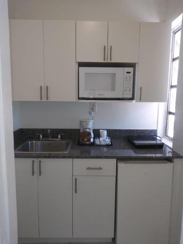 a white kitchen with a sink and a microwave at Beach Place Hotel in Miami Beach
