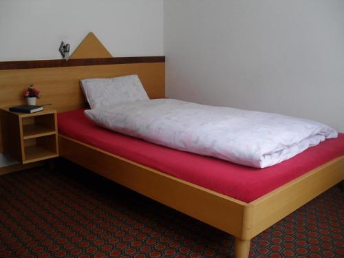 a bedroom with a bed with white sheets and a red blanket at Hotel Restaurant Aletsch in Mörel