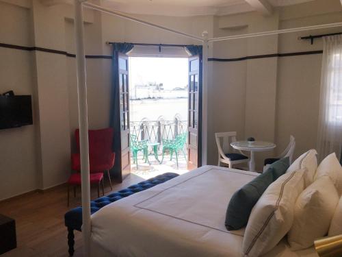 a bedroom with a bed and a balcony with a table at Hotel Conde de Penalba in Santo Domingo