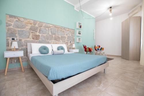 1 dormitorio con cama y pared de piedra en B&B Vico 10 en Guspini