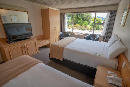 a hotel room with two beds and a flat screen tv at Kingsgate Hotel Te Anau in Te Anau
