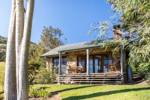 a stone house with windows and palm trees at Friday Creek Retreat in Coffs Harbour