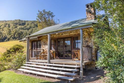 a small stone house with a porch and stairs at Friday Creek Retreat in Coffs Harbour