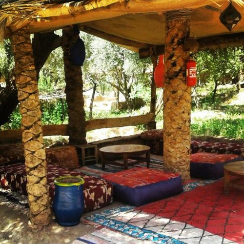 a pavilion with pillows and a table and a bench at Eco-Ferme Tamalait Skoura in Skoura