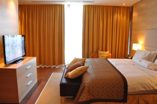 a bedroom with a bed and a flat screen tv at Hotel Grand Swiss in Erbil