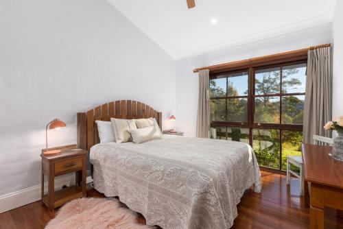 a white bedroom with a bed and a window at Friday Creek Retreat in Coffs Harbour