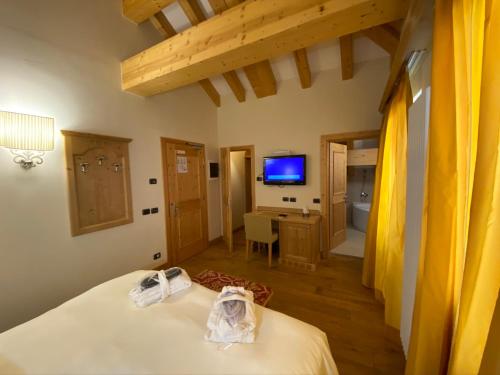 a bedroom with a bed and a desk and a television at Boutique Hotel Diana in Madonna di Campiglio