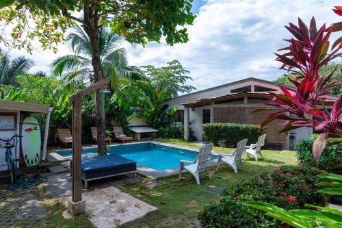 a backyard with a pool and chairs and a house at Maoritsio Garden Studios in Santa Teresa Beach