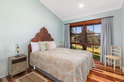 a bedroom with a bed and a chair and a window at Friday Creek Retreat in Coffs Harbour