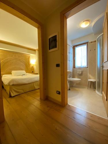 a bedroom with a bed and a tub and a sink at Boutique Hotel Diana in Madonna di Campiglio