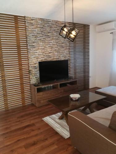 a living room with a flat screen tv on a brick wall at Gold Apartment in Strumica