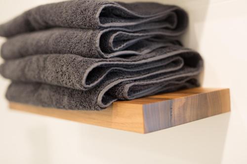 una pila de toallas negras en una estantería de madera en The Seabird, en Moruya