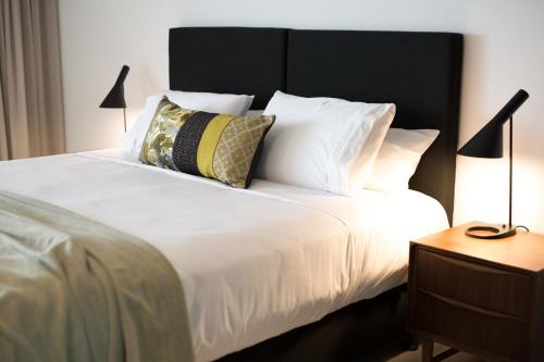 a white bed with a black headboard and pillows at The Seabird in Moruya