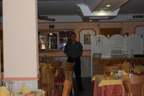 un hombre de pie en un comedor con mesas en Hotel Trajano, en Zalamea de la Serena