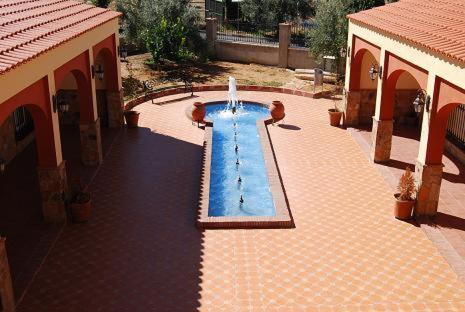 a swimming pool with a fountain in a courtyard at Hotel Trajano in Zalamea de la Serena