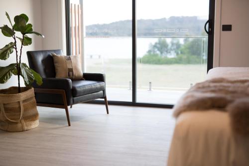 a bedroom with a chair and a plant in front of a window at The Seabird in Moruya