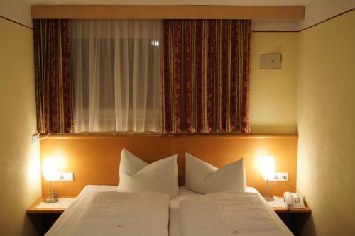 a bedroom with a bed with white pillows and a window at Sport Garni Kapplerhof – Ischgl/Kappl in Kappl