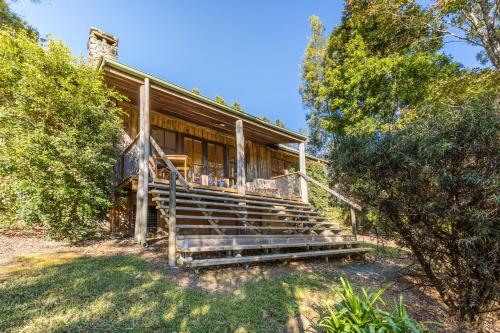 a wooden house with stairs in front of it at Friday Creek Retreat in Coffs Harbour