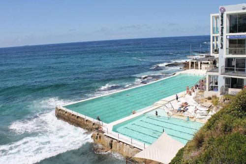 a swimming pool next to the ocean next to a building at Newly Renovated Sunny Studio - 5min Walk to Beach in Sydney
