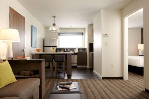 a living room and kitchen with a couch and a table at Hyatt House Indianapolis Fishers in Fishers