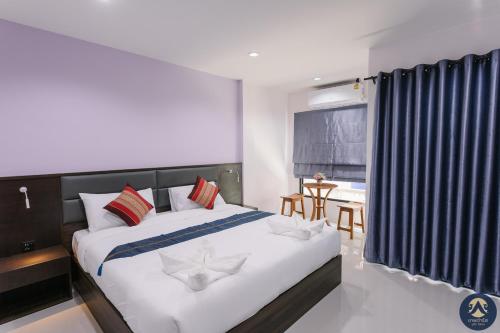 a bedroom with a large bed and a table at Thepchamrat Boutique Hotel in Uttaradit