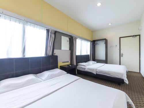 a hotel room with two beds and two windows at Raintree Hotel in Kuala Lumpur