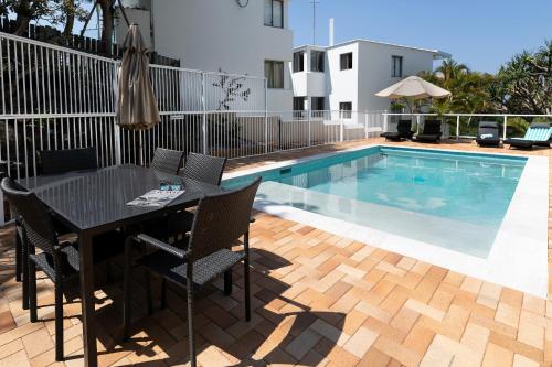 a dining table and chairs next to a swimming pool at Aqua Promenade Beachfront Holiday Apartments in Sunrise Beach