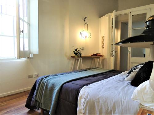 a bedroom with a bed with a blue blanket on it at Stylish duplex in Caseros Boulevard - San Telmo in Buenos Aires