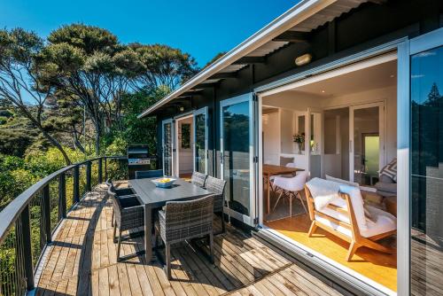 a deck with a table and chairs on a balcony at Te Kohanga, Oneroa in Oneroa