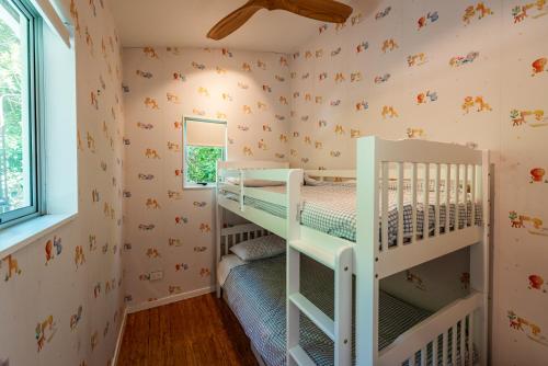 a childs room with two bunk beds and a window at Te Kohanga, Oneroa in Oneroa