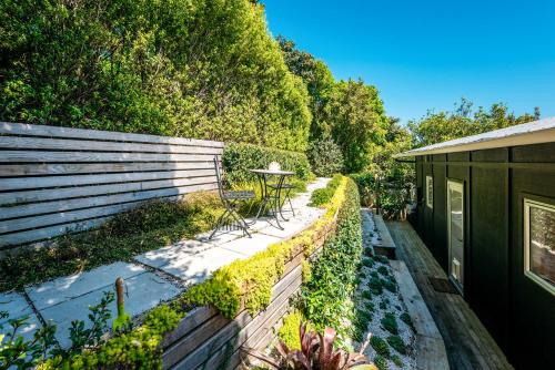 a garden with a fence and a table on a patio at Te Kohanga, Oneroa in Oneroa