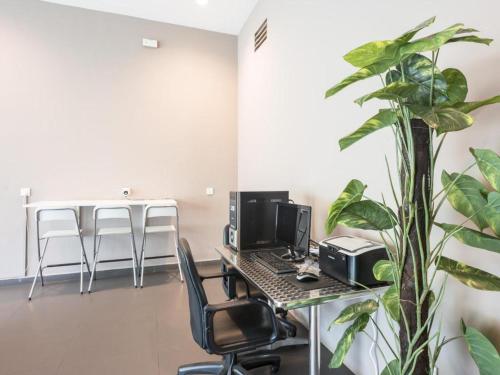 um escritório com uma secretária com um computador e uma planta em Raintree Hotel em Kuala Lumpur