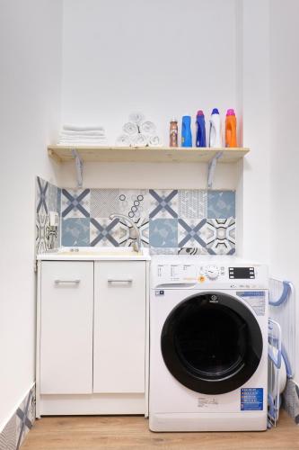 a washing machine in a laundry room with shelves at La Via del Porto Charme Rooms in Agropoli