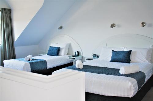 duas camas num quarto com azul e branco em Brougham Heights Motel em New Plymouth