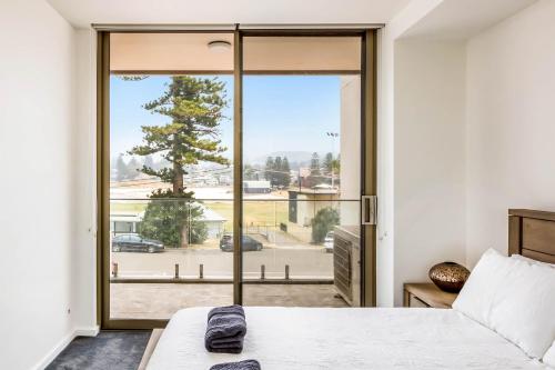 a bedroom with a bed and a large glass door at Bluewater Apartments in Kiama