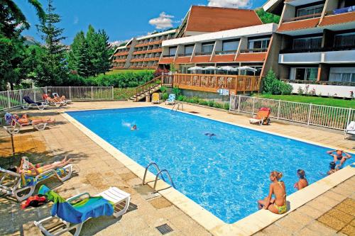 a large swimming pool with people sitting around it at Pierre et Vacances Serre Chevalier Chantemerle in Saint-Chaffrey