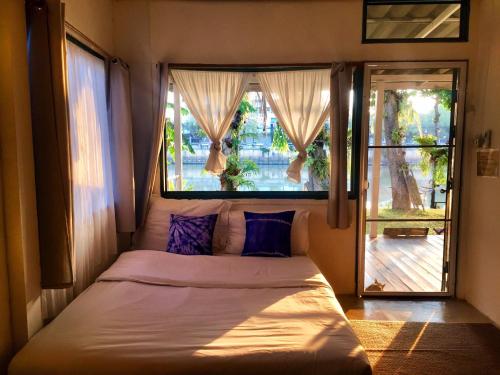 sypialnia z łóżkiem przed oknem w obiekcie Ban Narai River Guesthouse w mieście Chiang Mai