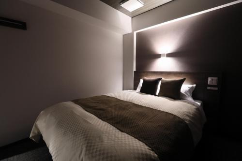 a bedroom with a bed with a light above it at The Celecton Tsuchiura Ekimae in Tsuchiura