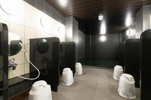 a bathroom with three urinals and three stalls in it at The Celecton Tsuchiura Ekimae in Tsuchiura