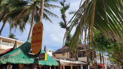 a group of palm trees and a building with signs at Nigi Nigi Nu Noos 'e' Nu Nu Noos in Boracay