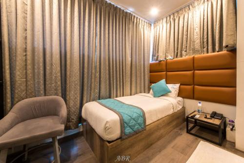 a small bedroom with a bed and a chair at Caramel Hotels in Bengaluru