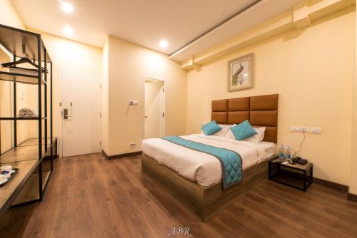 a bedroom with a large bed with blue pillows at Caramel Hotels in Bangalore